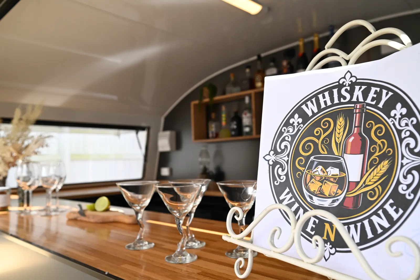 Martini glasses lined up on the timber bar top with the Whiskey N Wine sign